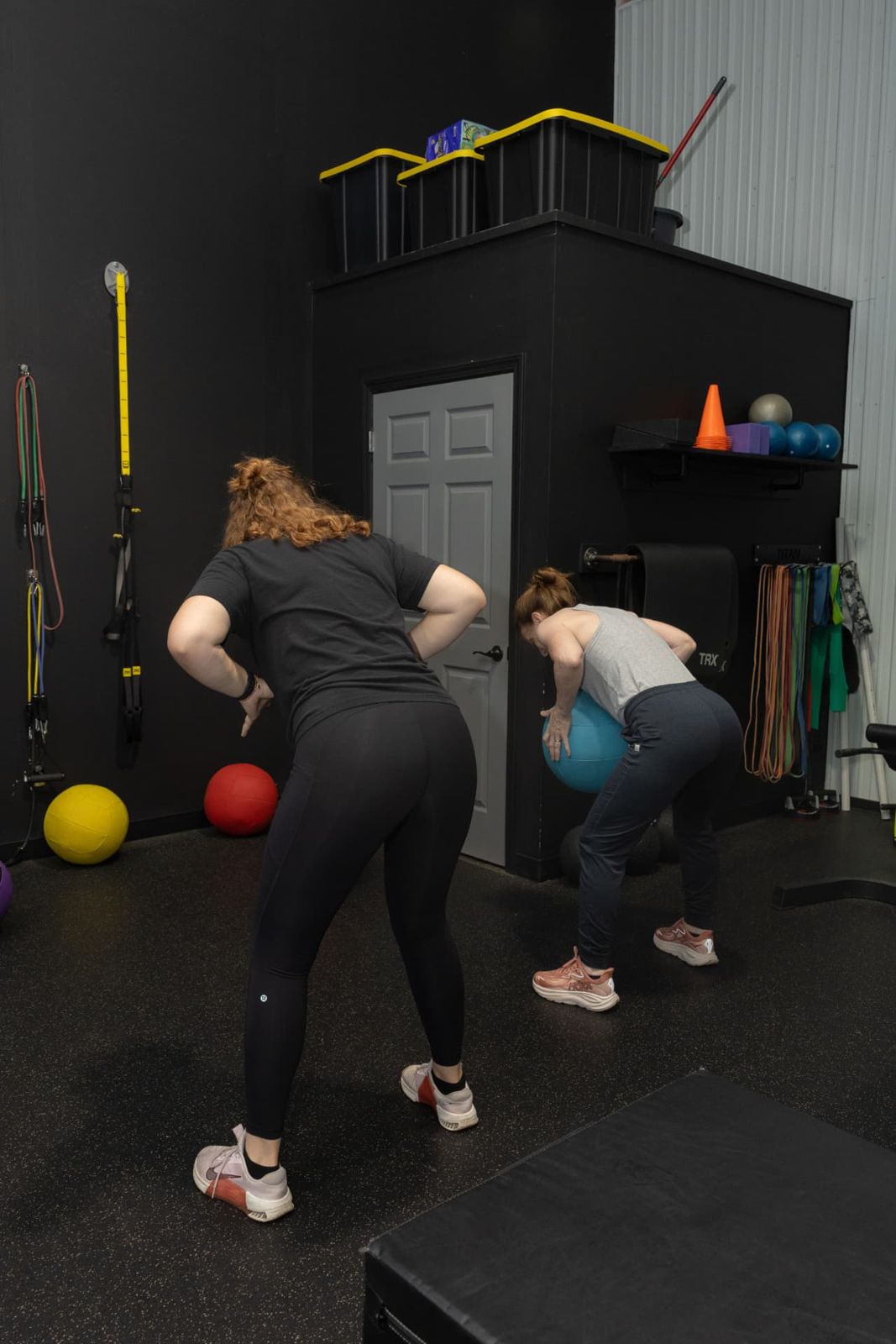 Coach cueing a member through a hip hinge with a stability ball