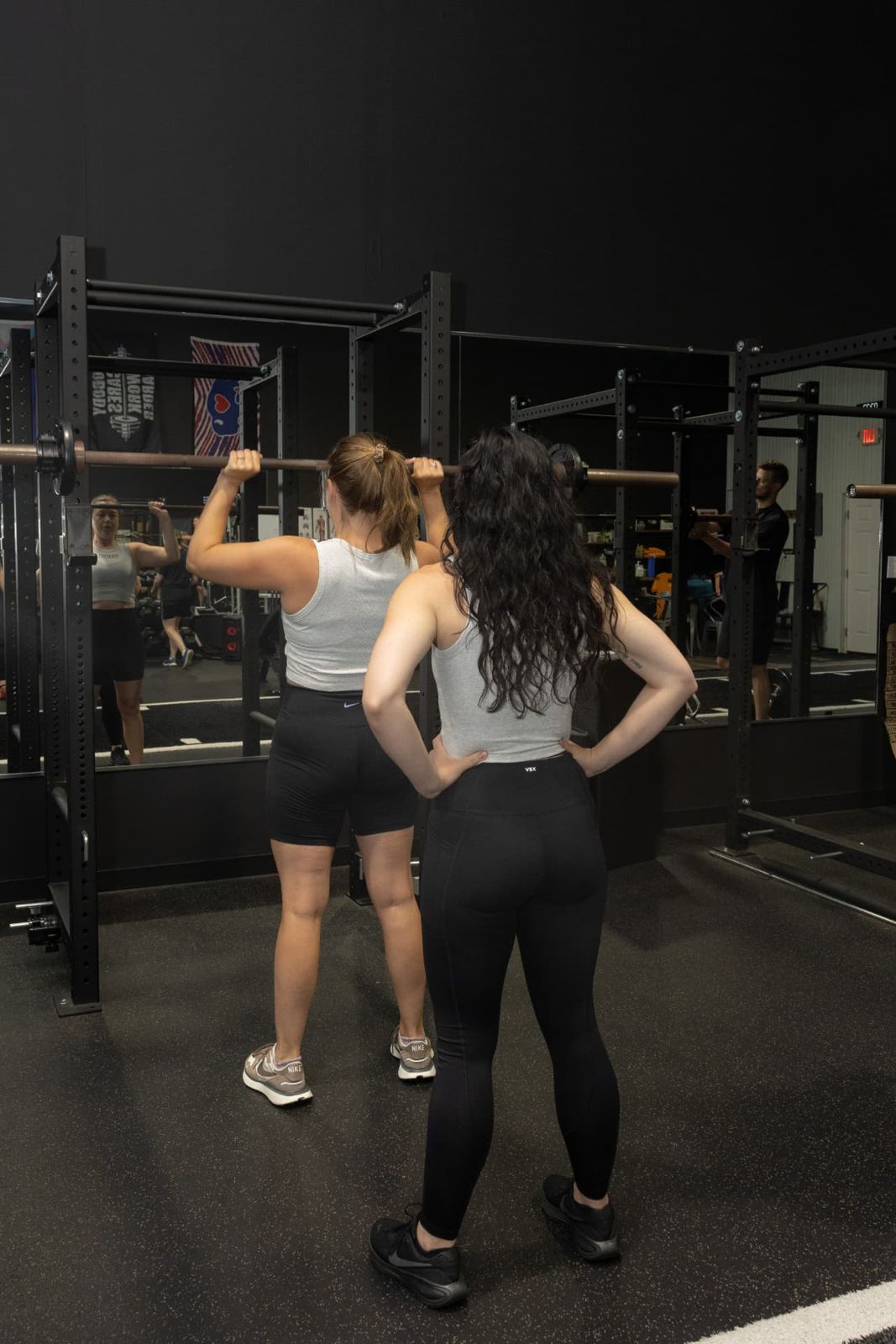 Coach teaching barbell squat setup to a member at RockeyFit